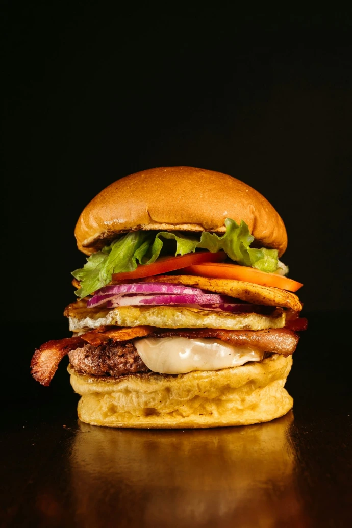 a hamburger with bacon, lettuce, tomato, and cheese